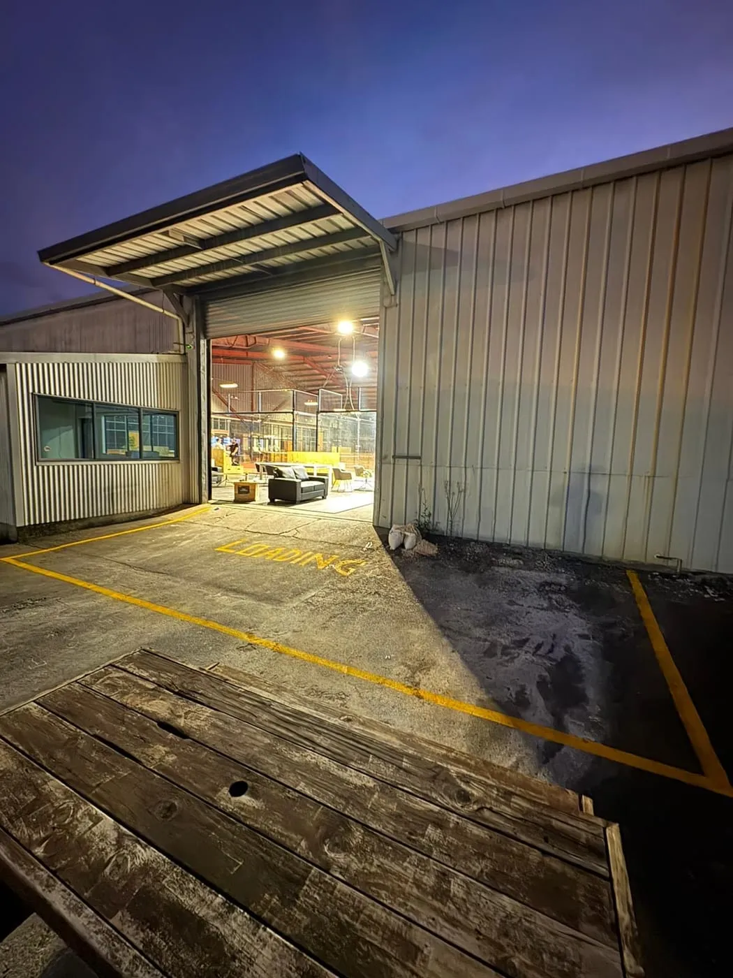 The Padel Park roller door open at dusk, the lit courts and lounge inside