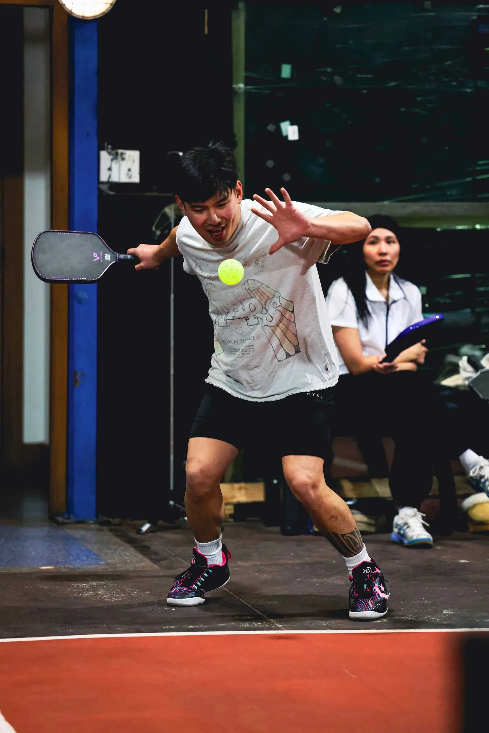 A pickleball player stretching for a volley