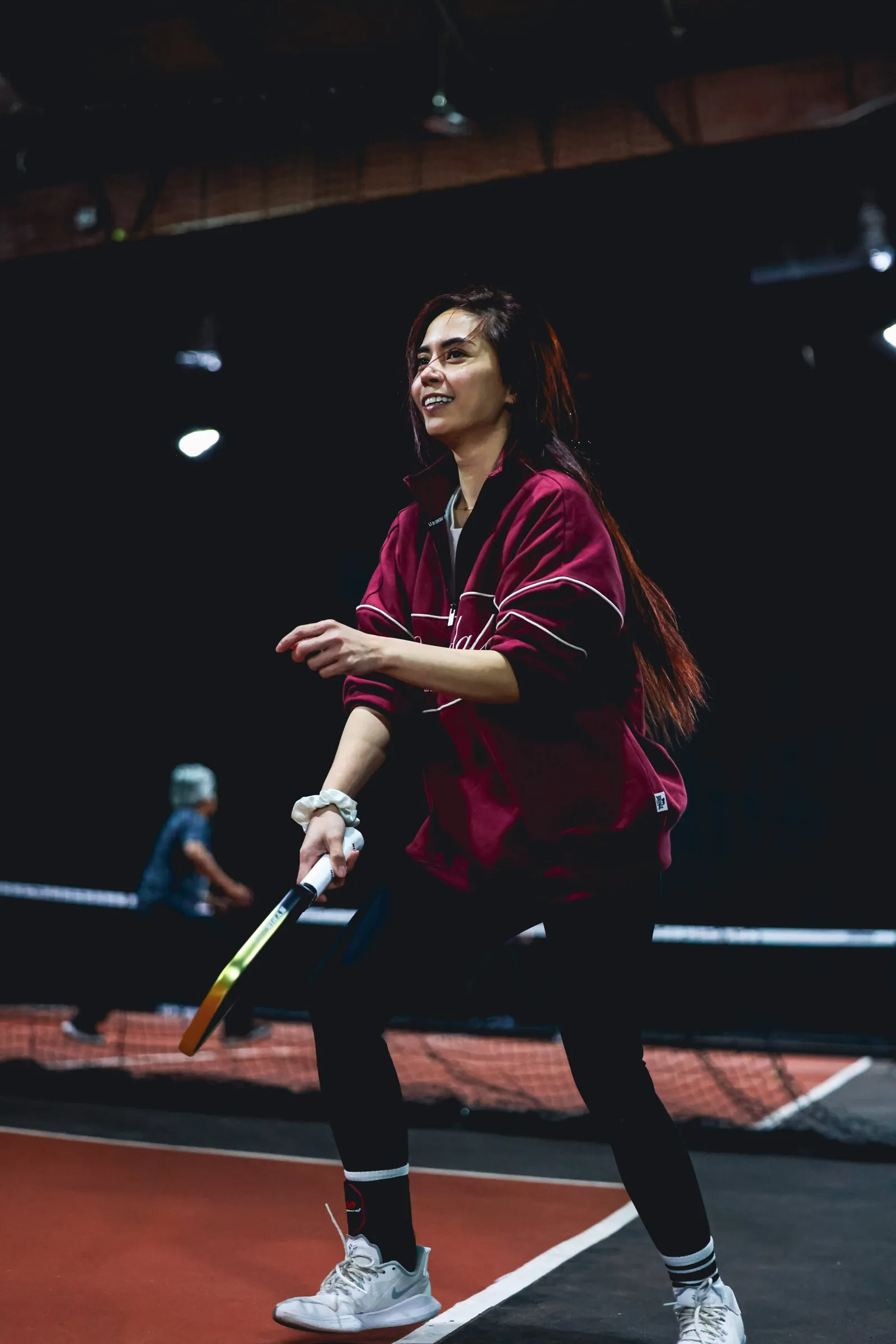 A player smiling mid-rally on a pickleball court