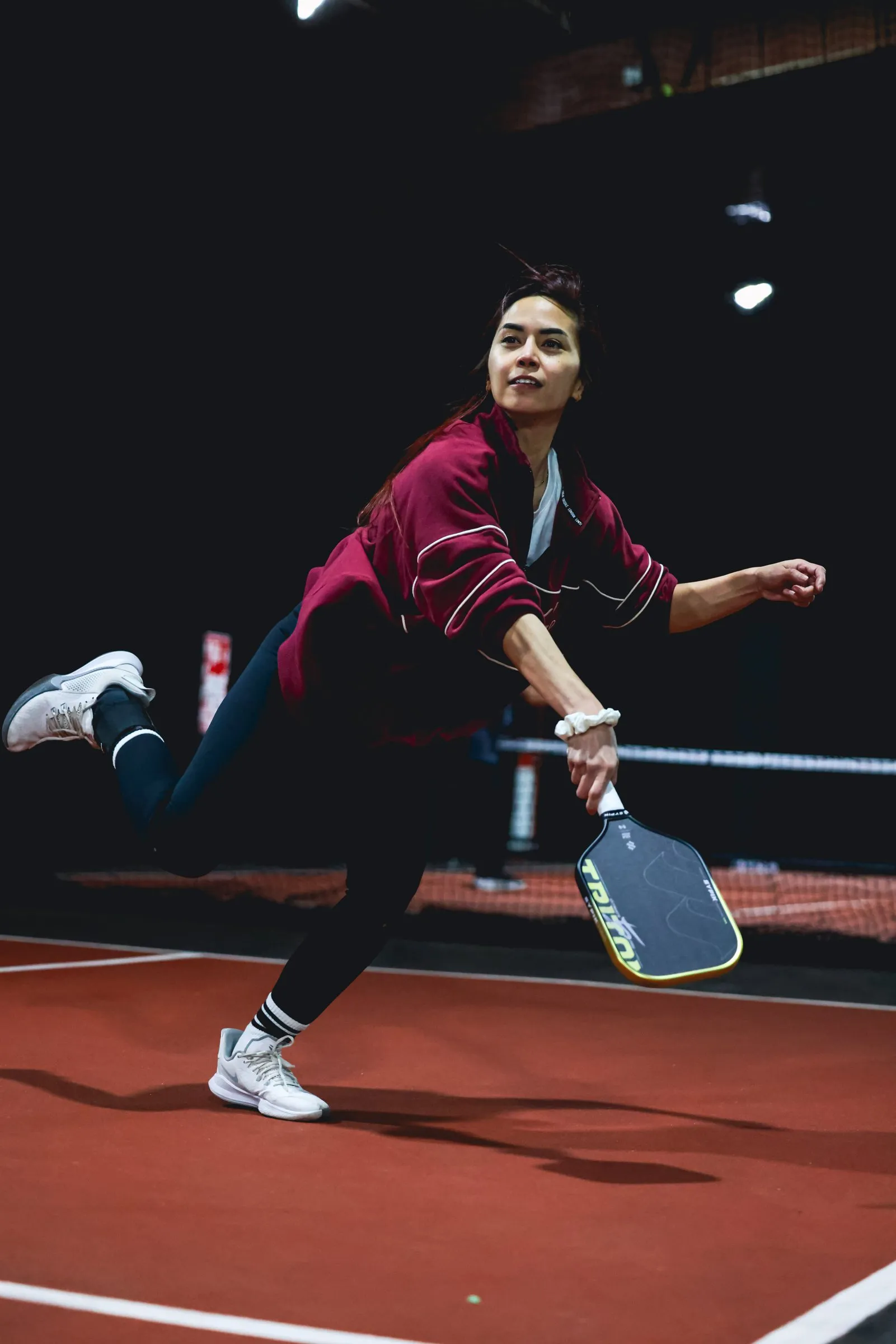 A pickleball player lunging for a low ball
