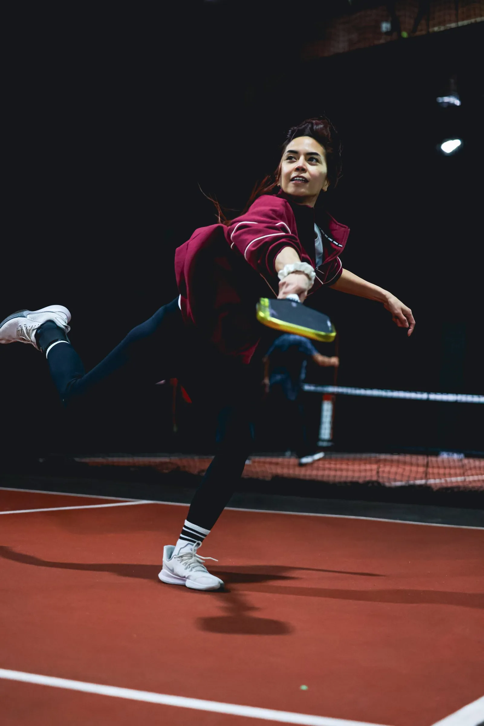 A pickleball player reaching wide for a shot