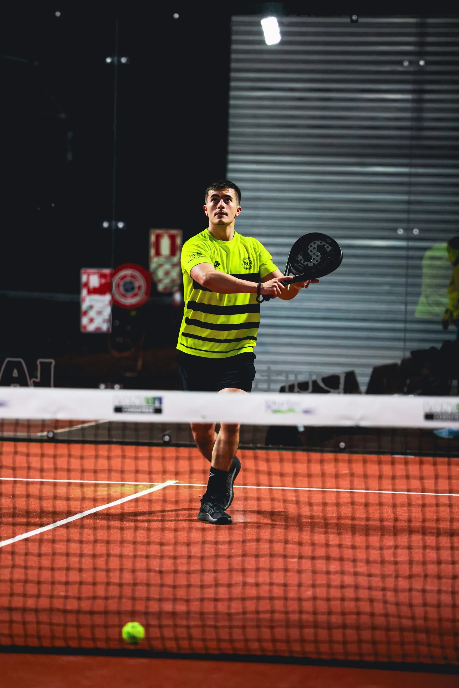 A padel player at the net with the court lines behind