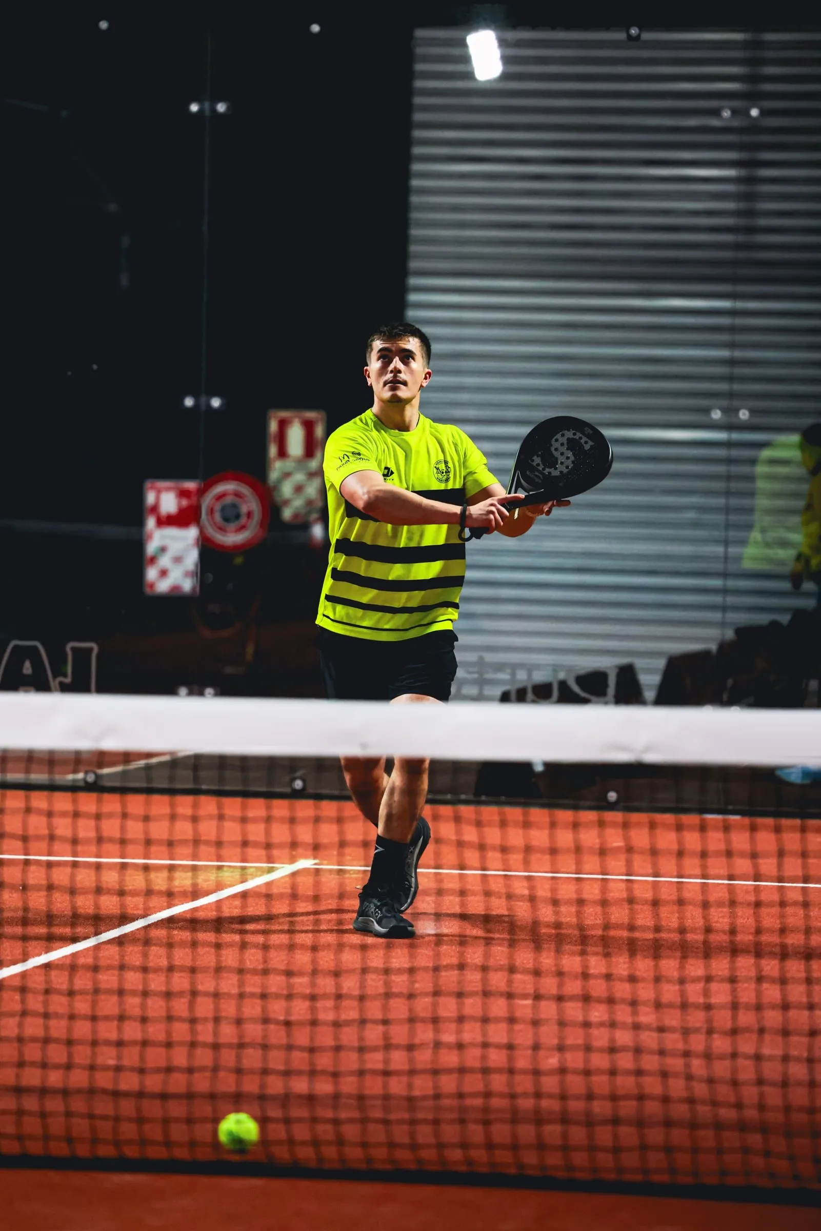 A padel player at the net with the court lines behind