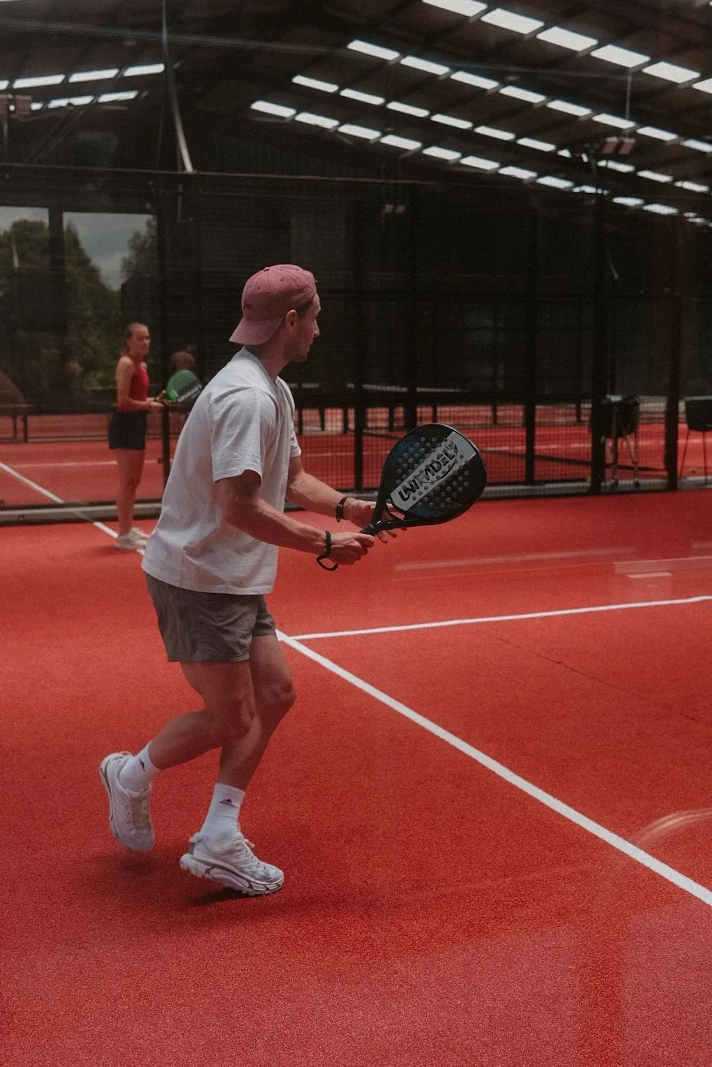A player walking onto a padel court in daylight
