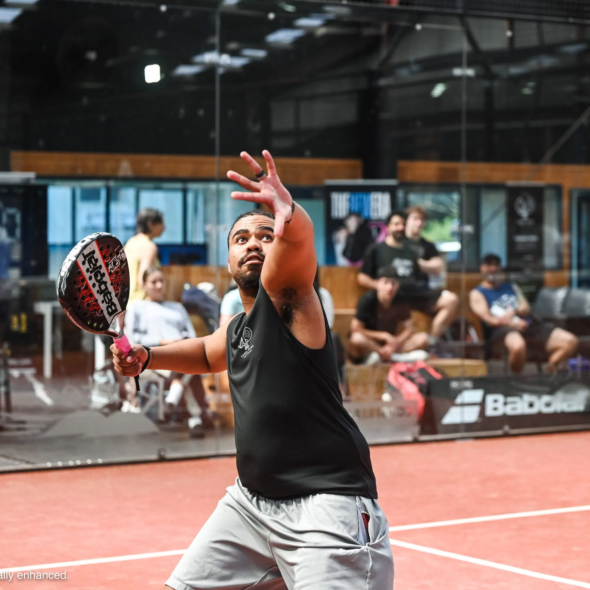 A padel player lining up an overhead
